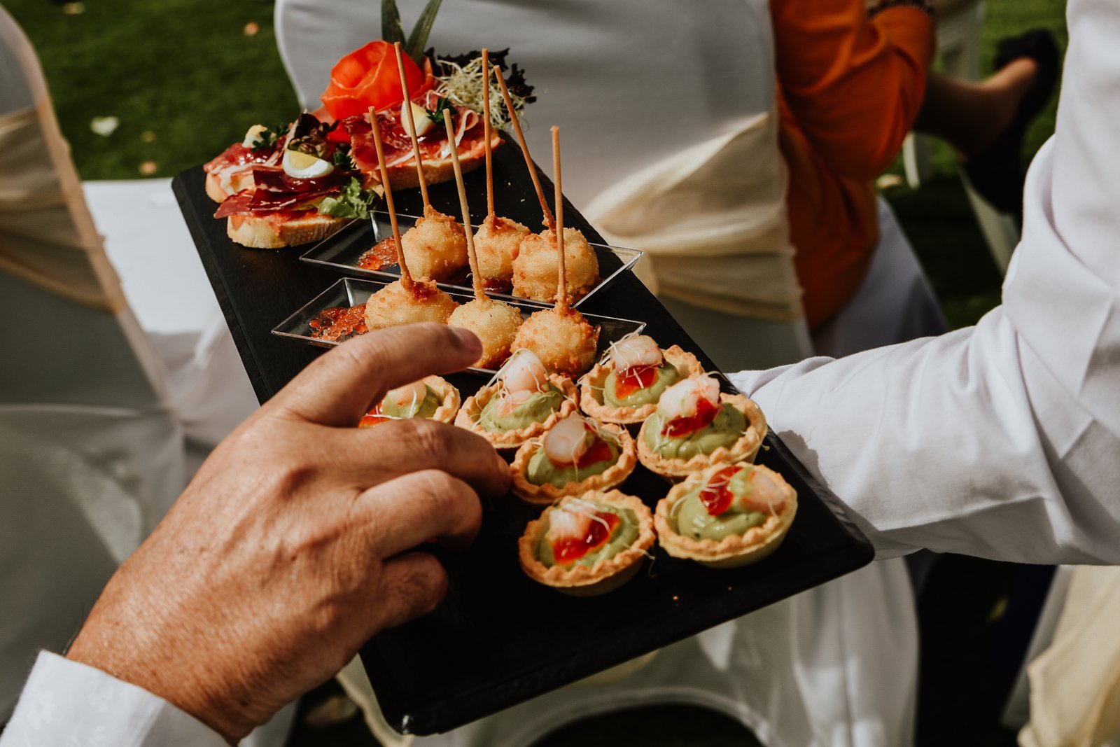 A chef proudly presents a beautifully arranged dish of grilled chicken adorned with fresh cherry tomatoes and herbs.